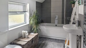 A bathroom with a toilet, a wooden chest, a bathtub, a sink, and a potted plant. - 2 bedroom accommodation in Beverley (Beverley)
