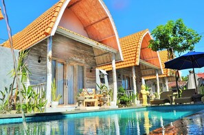 A resort with a swimming pool, wooden villas with tiled roofs, and outdoor seating areas. - The Box Paradise Bungalow (Penida Island)