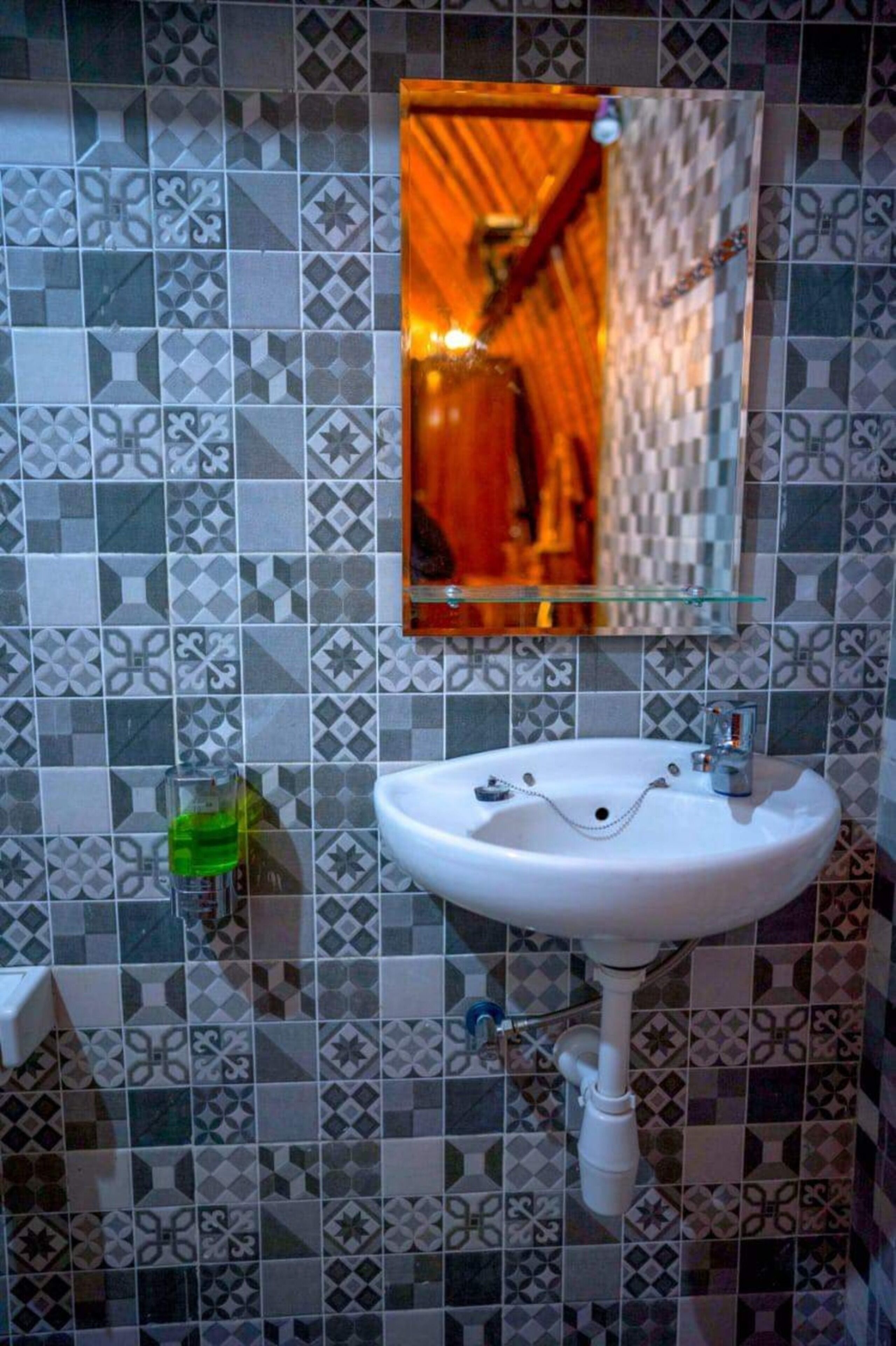 Een badkamer met een witte wasbak, een spiegel en betegelde wanden.