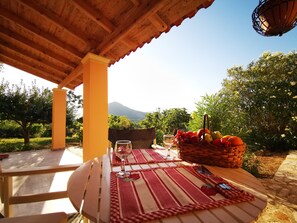 A wooden table with a red and white checkered tablecloth, a glass of wine, and a fruit basket. - AELIA  APARTMENT  ERMONES CORFU (Corfu)