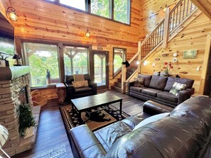 A cozy cabin interior with a fireplace, leather sofas, a coffee table, and a staircase. - South Side Serenity 2 Bedroom Cabin by RedAwning (Sevierville)