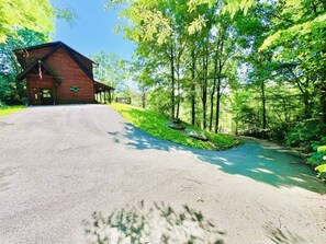 A building with a sloped roof, a flag, and a paved driveway leading to it. - South Side Serenity 2 Bedroom Cabin by RedAwning (Sevierville)