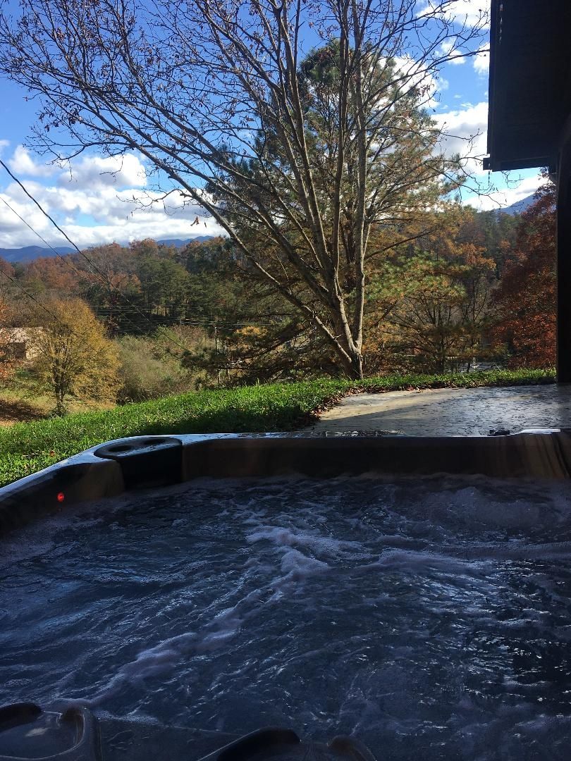 A hot tub with a view of a forest and mountains.