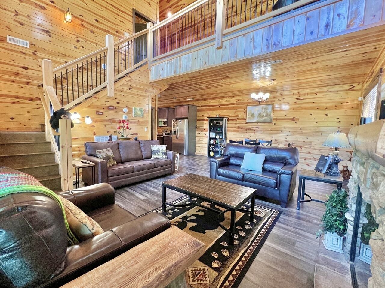 A spacious living area with a wooden interior, a staircase, and a fireplace.