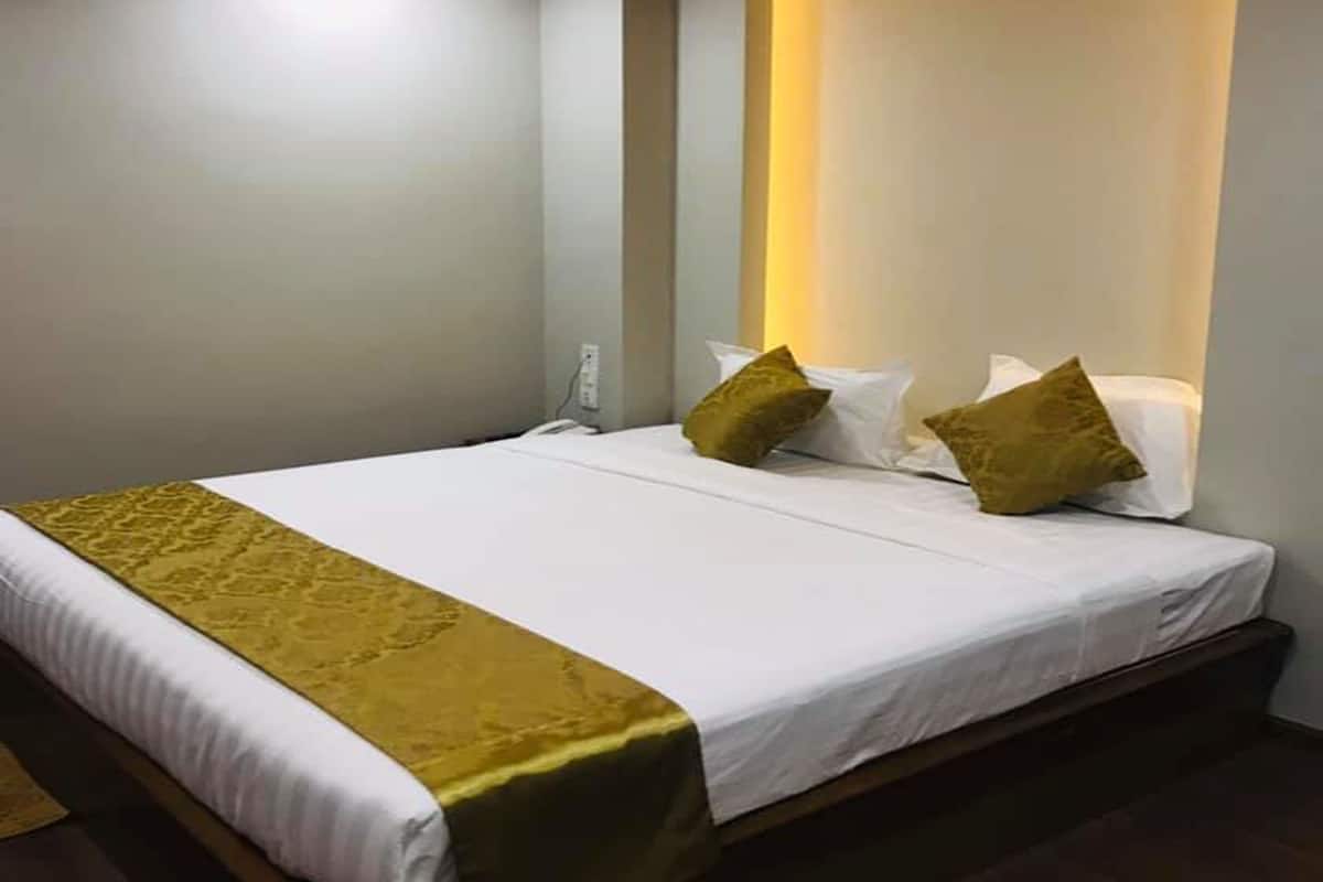 Habitación de hotel con cama, mesita de noche y luz empotrada en la pared.