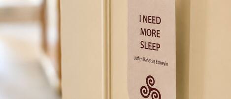 A door with a sign that reads 'I NEED MORE SLEEP' and a name 'Lütfen Rahatsiz Etmeyin'.