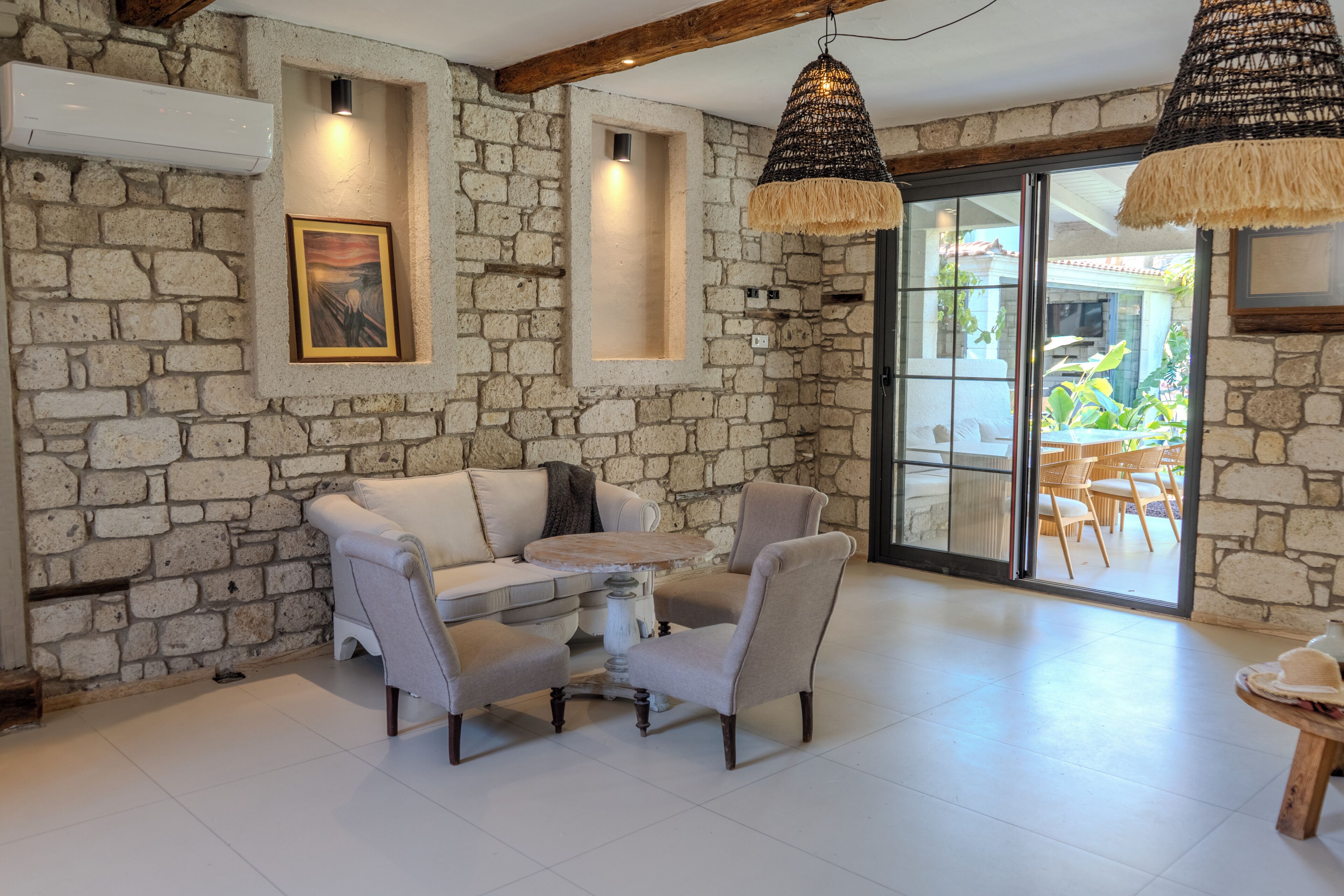 A room with stone walls, a sofa, a coffee table, and a dining area with chairs.