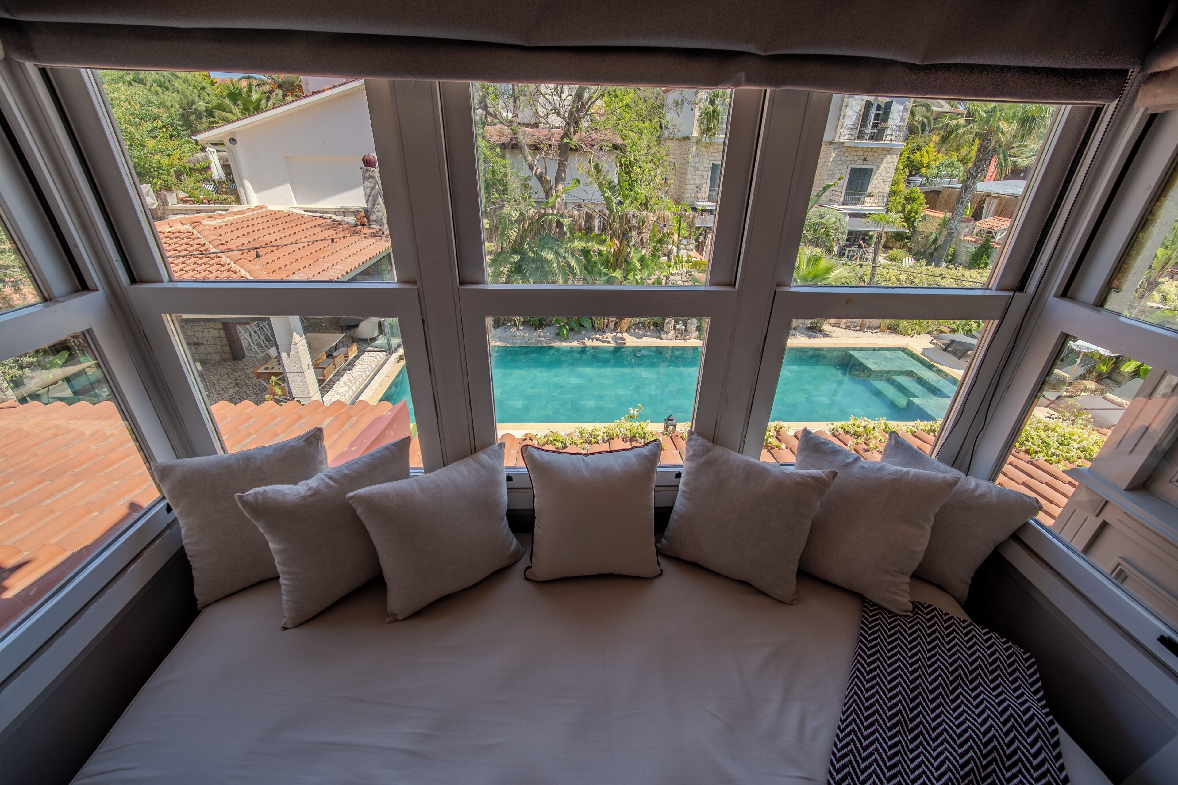 Un lit donnant sur une piscine, grâce à de grandes fenêtres.