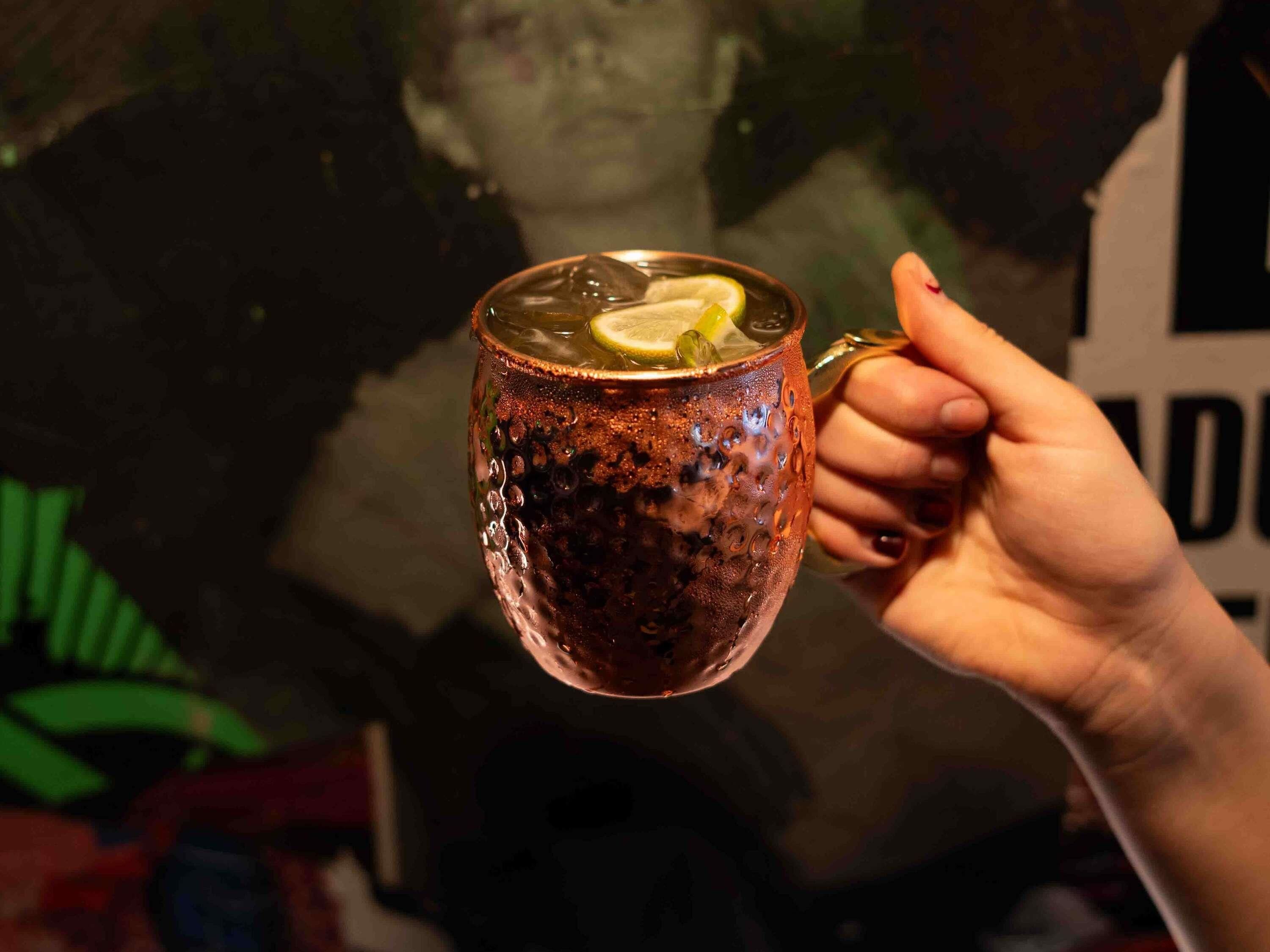 Una mano sosteniendo una taza texturizada con una rodaja de limón.