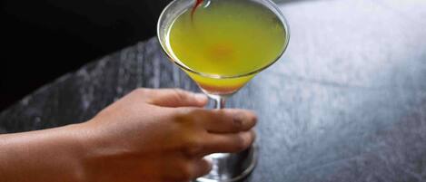 A hand holding a glass with a yellow liquid.