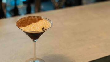 Una copa de martini con espuma sobre una barra.