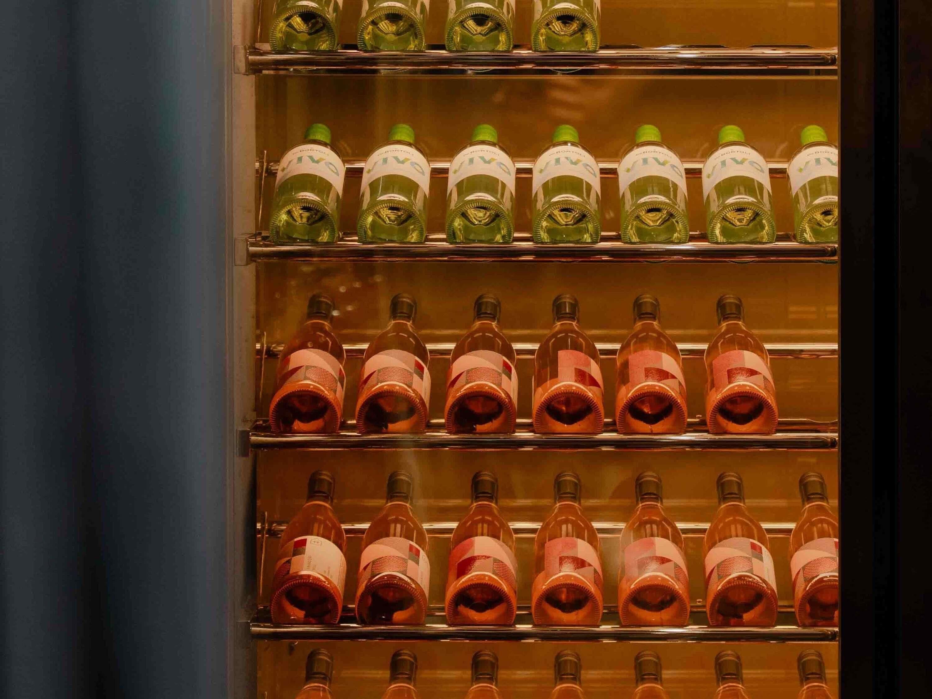 A refrigerated display case with multiple shelves containing bottles.