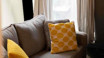 A grey sofa with a yellow pillow and a yellow cushion.
