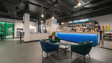 Un área de bar moderna con mostrador, asientos y una puerta verde al fondo.