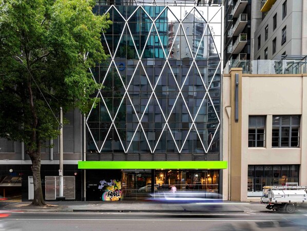 Un edificio moderno con fachada de vidrio geométrico y toldo verde.