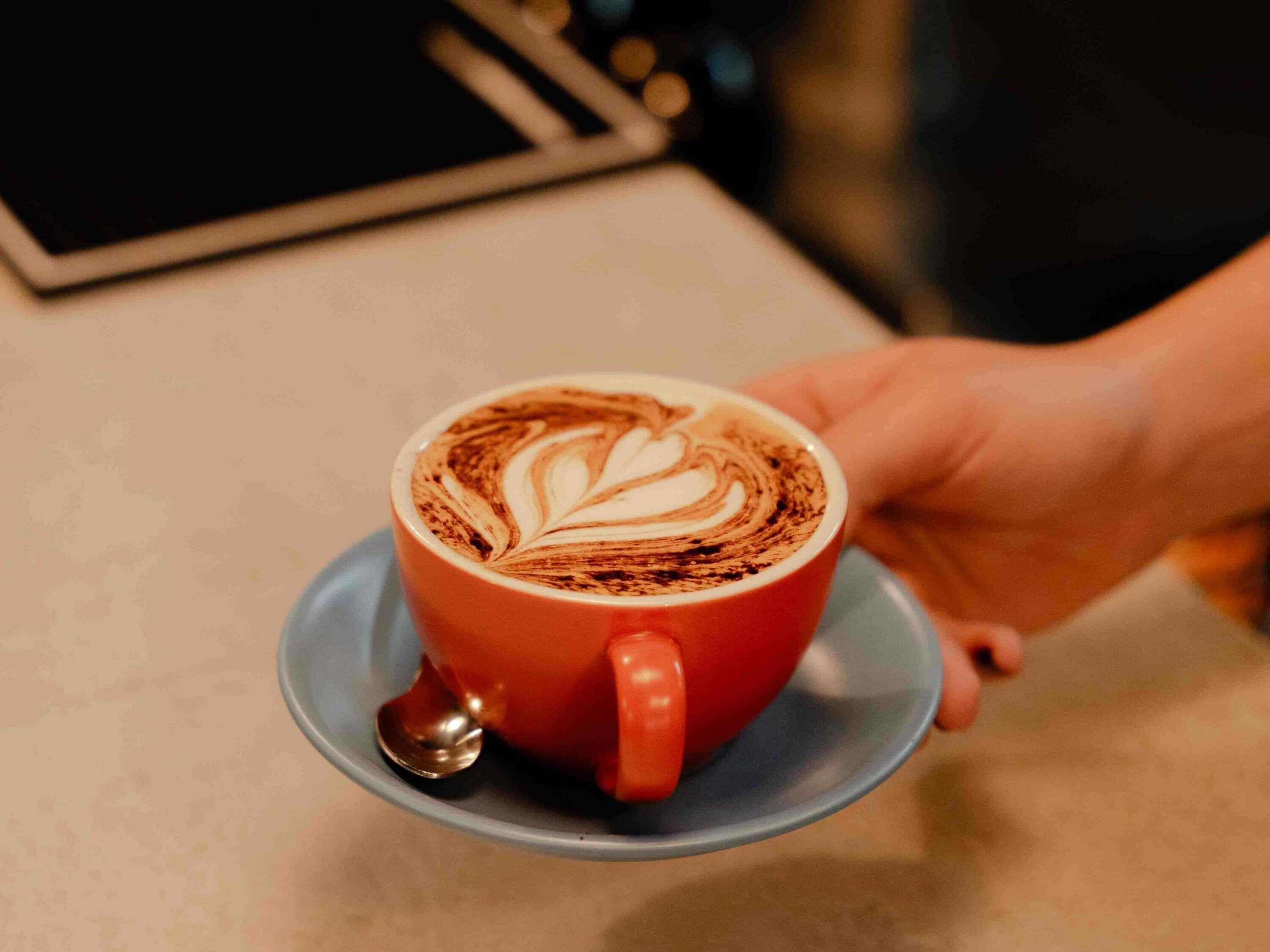 Une tasse de café avec un motif en latte sur une soucoupe.