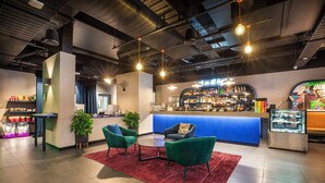 A bar area with a counter, two green chairs, a red rug, and a display case.