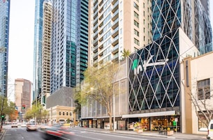 A hotel with a modern glass facade, located in a busy urban area with tall buildings.
