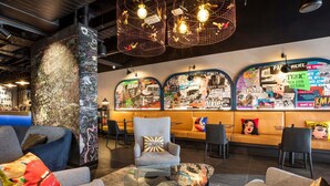 A modern lounge area with seating, a coffee bar, and a wall decorated with event posters.