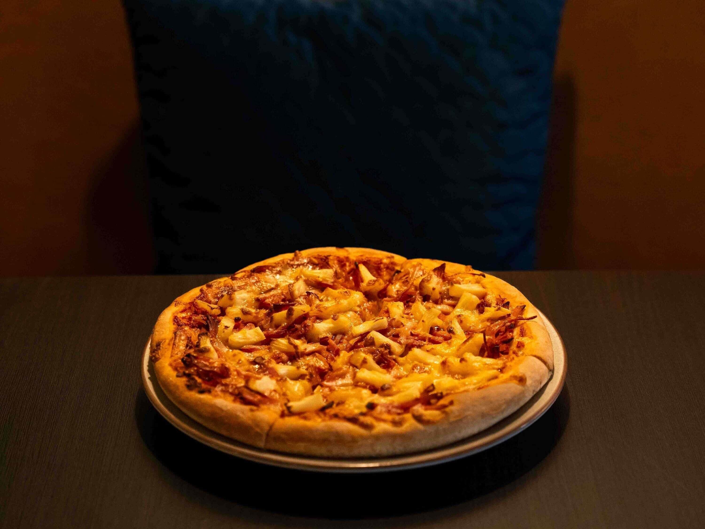 Une pizza sur un plateau rond en métal, posée sur une table.