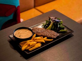 A plate with a steak, fries, and a salad on a dark table.
