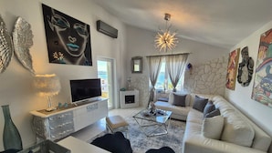 A modern living room with a sofa, TV, decorative items, and artwork. - Apartment Sonja (Klimno - island Krk)