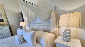 A neatly made bed with a canopy, a bedside lamp, and a small cabinet. - Apartment Sonja (Klimno - island Krk)