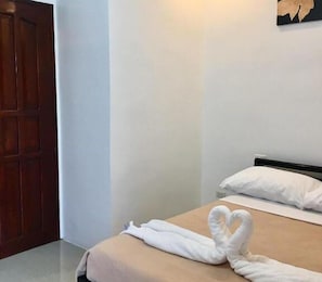 Una habitación de hotel con una cama, una puerta de madera y una pared blanca.