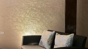 Une pièce avec un mur à texture, un canapé de couleur sombre agrémenté de coussins à motifs et une prise électrique visible.