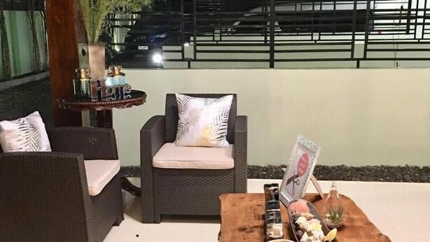 Un espace extérieur aménagé avec des chaises en osier et une petite table agrémentée d’objets décoratifs.