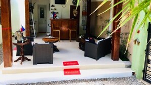 Un espace d’accueil comprenant un bureau en bois, deux chaises, un canapé et une pancarte « Bienvenue ».