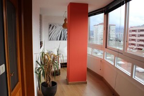 Une pièce dotée d’une grande fenêtre, d’une plante en pot, d’une décoration murale à rayures zébrées et d’une porte en bois.