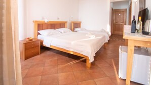 A bedroom with two single beds, a wooden nightstand, a desk with a chair, a mirror, and a door leading to another room. - Levantin Inn 1,3 Room N8 Sea Side (Sveti Stefan)