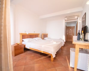 A bedroom with two single beds, a wooden nightstand, a desk with a chair, a mirror, and a door leading to another room. - Levantin Inn 1,3 Room N8 Sea Side (Sveti Stefan)