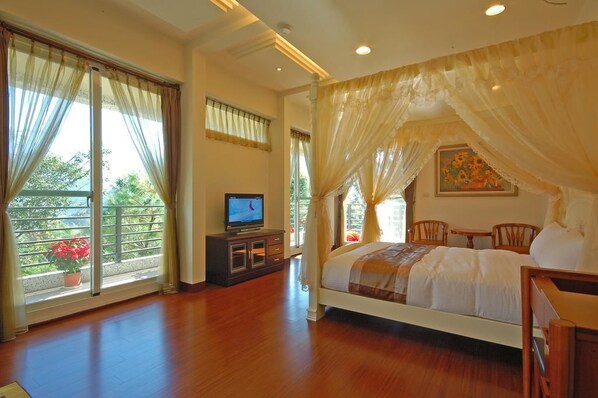 A bedroom with a bed, a TV on a cabinet, a balcony with curtains, and a painting on the wall. - Ti Siang B&B (Ren'ai)