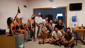 A group of people in a room with a whiteboard, a fan, and a television on the wall. - Backpackers Villa (Arugam Bay)