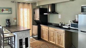 A compact kitchen with wooden cabinets, a black stove, and a stainless steel refrigerator.