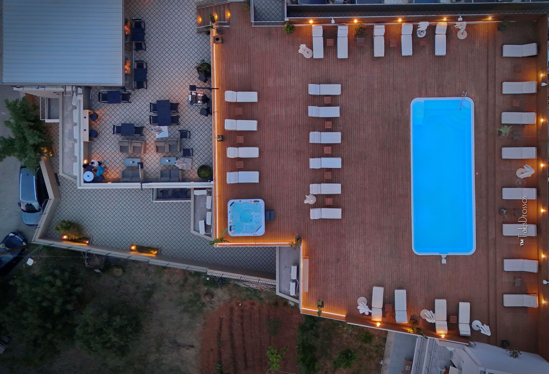 An aerial view of a rooftop with a swimming pool, sun loungers, a hot tub, and outdoor seating areas.