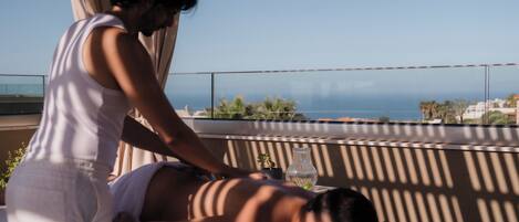 Une séance de massage sur un balcon offrant une vue sur la côte.