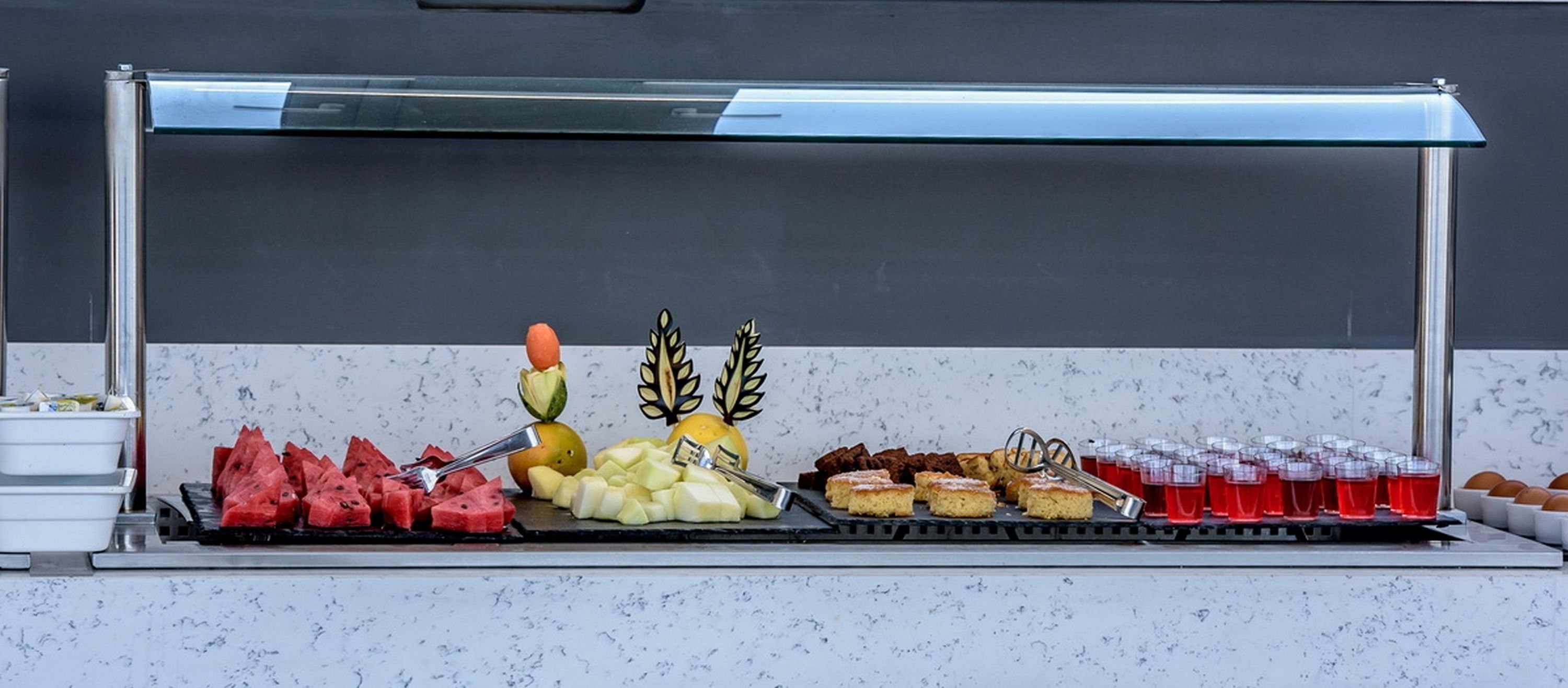 A buffet with various food items including watermelon, apples, and desserts.