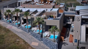 A modern hotel with a rooftop pool area, multiple lounge chairs, and a glass-enclosed pool.