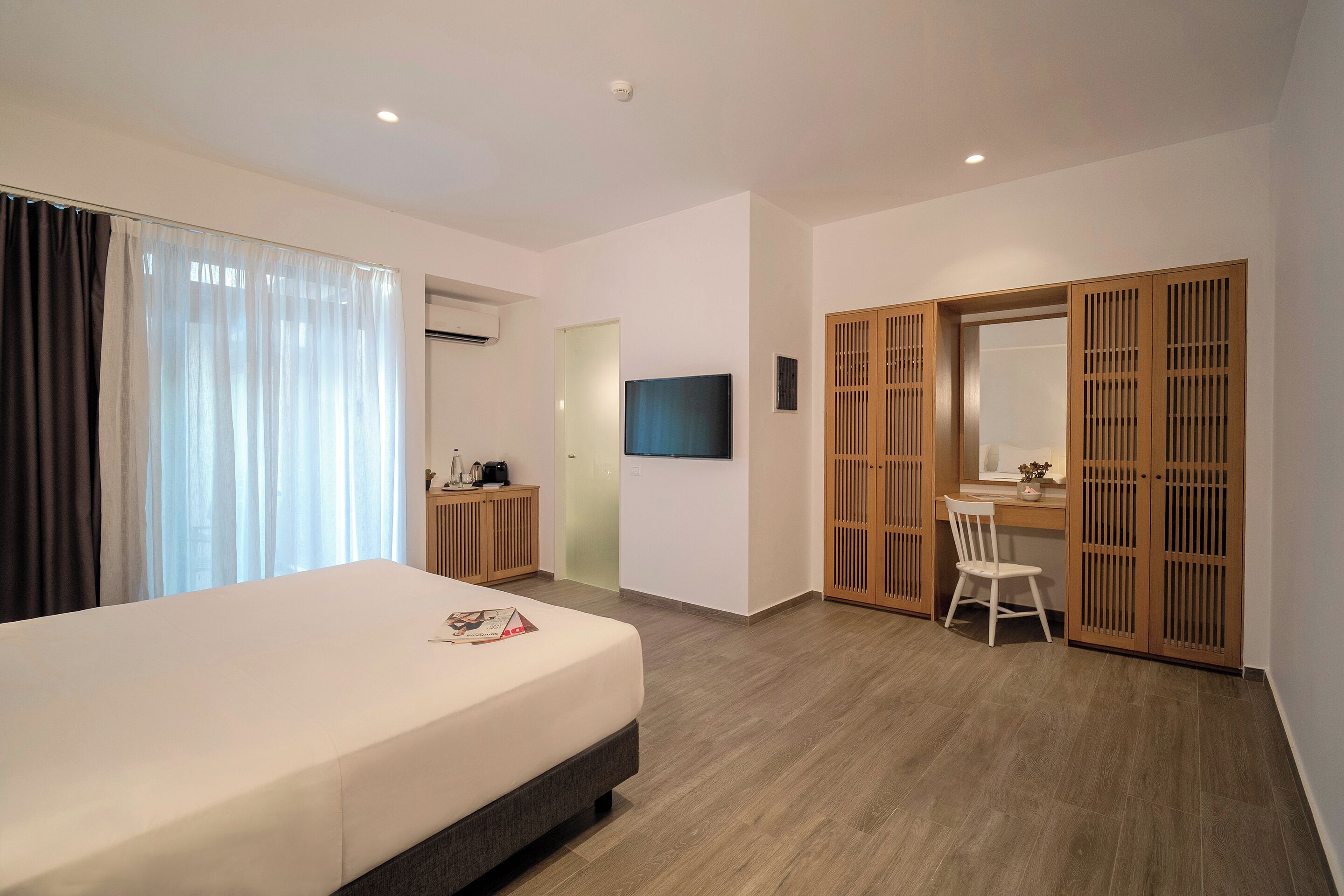 Una habitación de hotel con cama, escritorio, silla, televisor y armario.