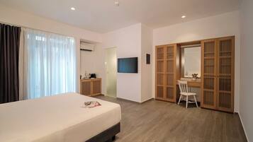Una habitación de hotel con cama, escritorio, silla, televisor y armario.