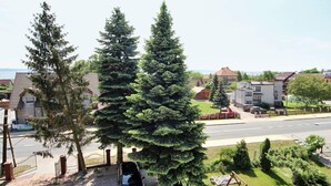 Une rue résidentielle bordée de maisons, avec une voiture garée et un grand arbre à feuilles persistantes.