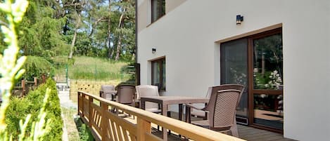 Une terrasse extérieure moderne, dotée d’une plateforme en bois, d’un espace salon et offrant une vue sur une zone boisée.