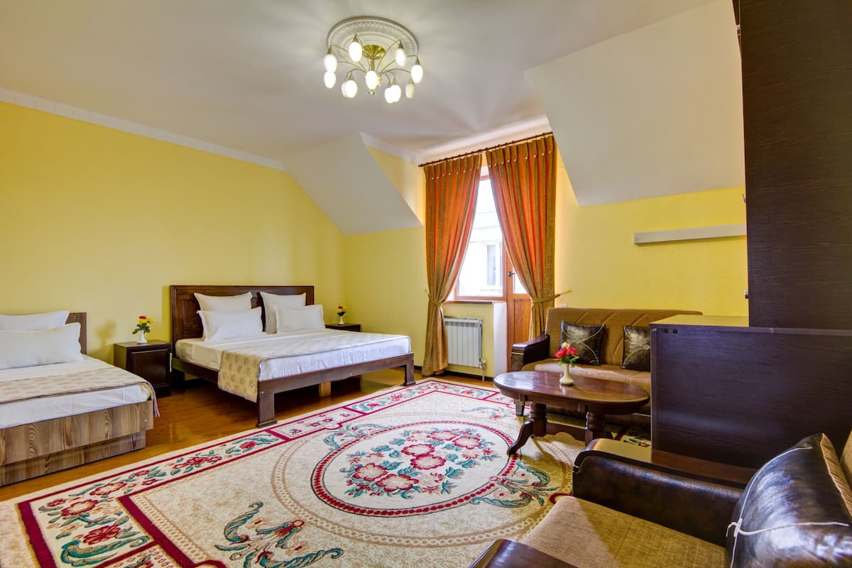 Una habitación con dos camas, un sofá, una mesita y un candelabro.