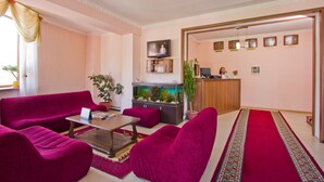 A living room with a red carpet, a fish tank, and a TV. - King House hotel (Bishkek)