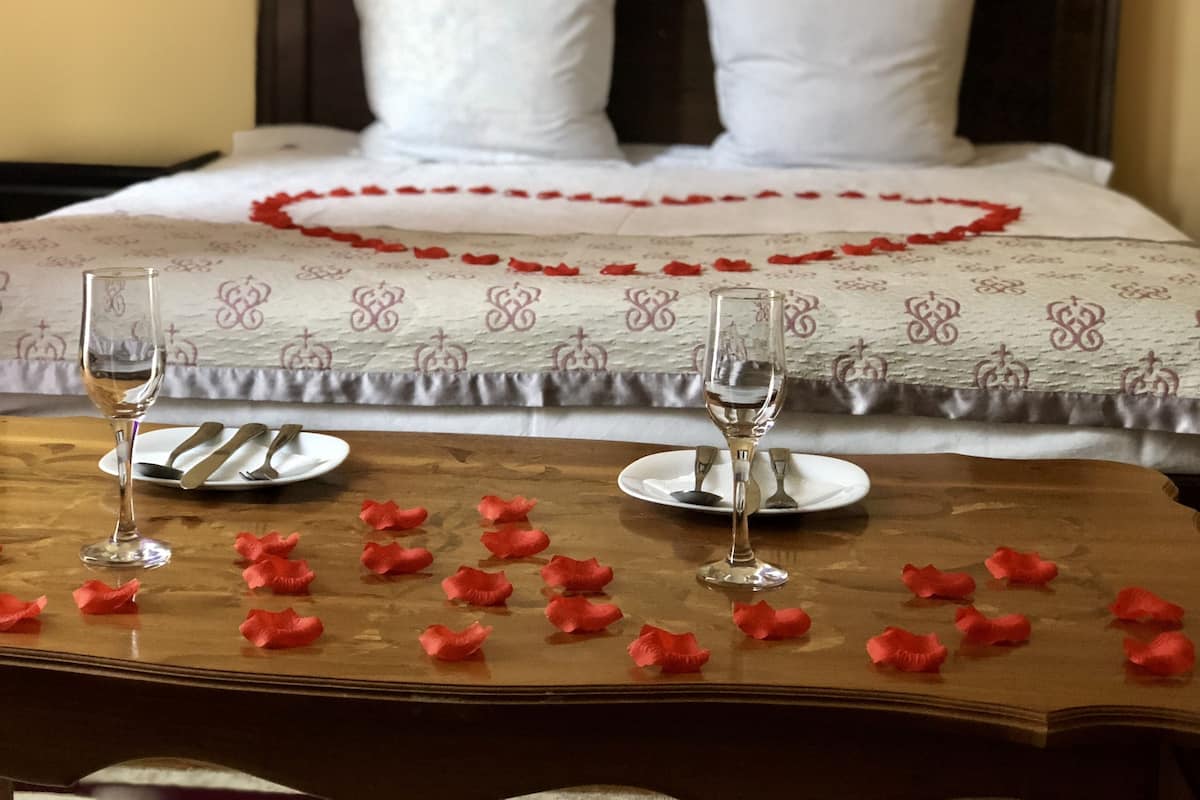 Una cama bien hecha con sábanas blancas y una decoración en forma de corazón rojo sobre la colcha.