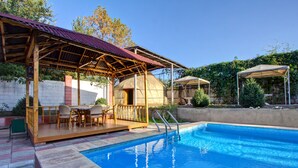 A swimming pool with a wooden deck, a covered seating area, and a large dome structure. - King House hotel (Bishkek)