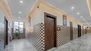 A modern hotel corridor with patterned walls, a marble floor, and recessed lighting. - Hotel Bhawani International (Reasi)